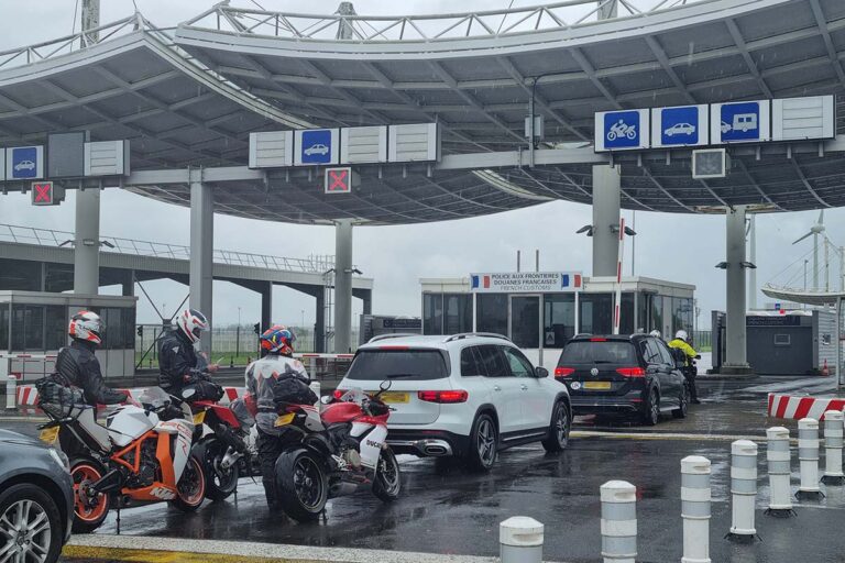 French customs gate at the Eurotunnel with cars and motorcycles waiting in line.