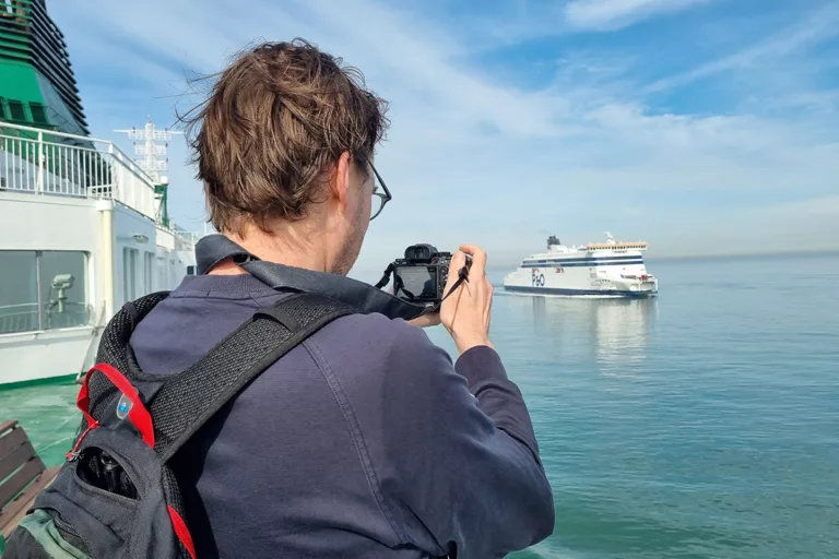A team member from the website Calais-Dover.com is taking a photo of the passing P&O ferry Spirit of France.