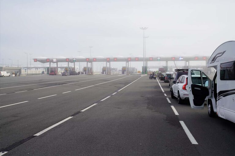 A line of motorcycles, cars, and campers at the check-in gates of Irish Ferries in the port of Calais.